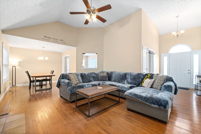 living room with a textured ceiling, wood-type flooring, ceiling fan with notable chandelier, and high vaulted ceiling