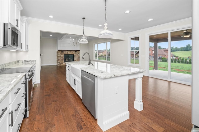 kitchen featuring sink, a kitchen island with sink, white cabinetry, stainless steel appliances, and light stone countertops