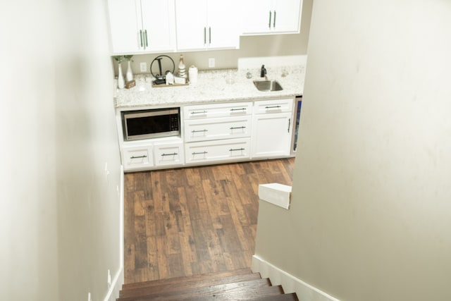 kitchen featuring sink, dark hardwood / wood-style flooring, white cabinetry, and light stone countertops