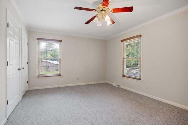 spare room featuring ceiling fan, ornamental molding, a healthy amount of sunlight, and carpet