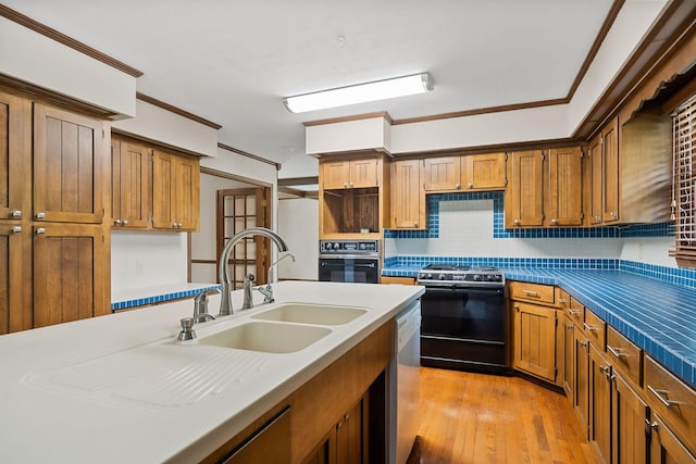 kitchen featuring sink, crown molding, light hardwood / wood-style floors, decorative backsplash, and black appliances