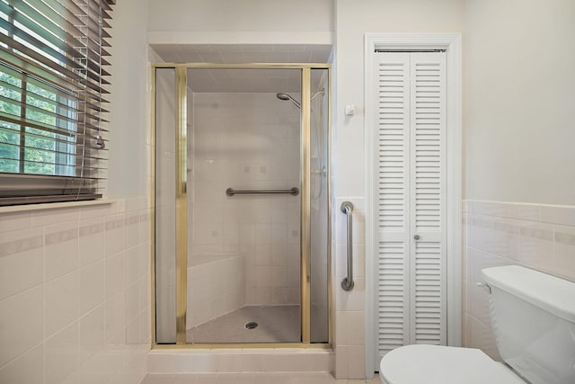 bathroom with toilet, an enclosed shower, and tile walls