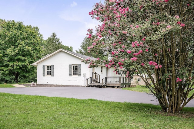 rear view of property featuring a yard and a deck