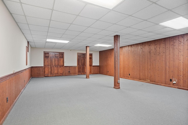 basement with a paneled ceiling and light colored carpet