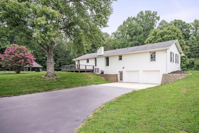 raised ranch featuring a garage, a deck, and a front lawn