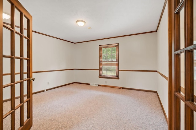 carpeted empty room featuring crown molding and french doors