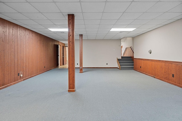 basement with a paneled ceiling and light colored carpet