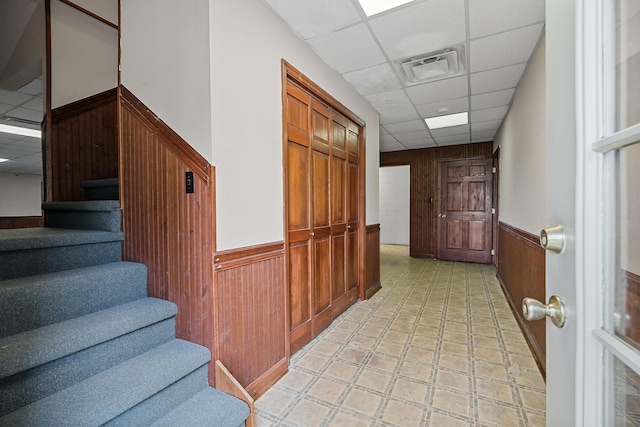 corridor featuring a drop ceiling and wood walls