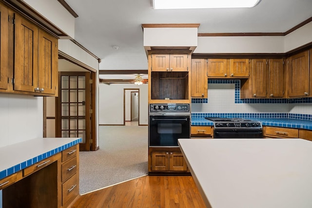 kitchen with ornamental molding, ceiling fan, hardwood / wood-style floors, decorative backsplash, and black appliances