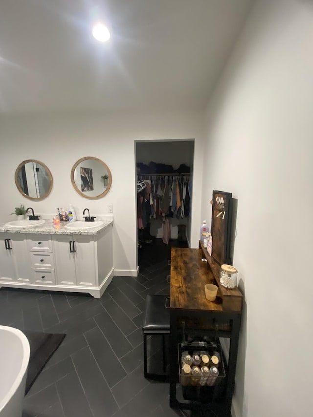 interior space featuring tile patterned flooring, vanity, and a bathing tub