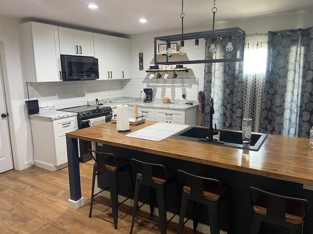 kitchen featuring white cabinetry, light wood-type flooring, wood counters, and black appliances