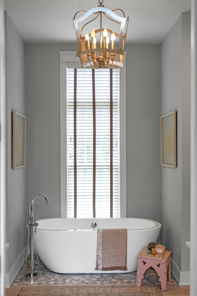 bathroom featuring a washtub, a notable chandelier, and hardwood / wood-style flooring