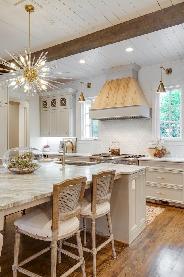 kitchen featuring custom exhaust hood, hanging light fixtures, a kitchen island with sink, and dark hardwood / wood-style flooring