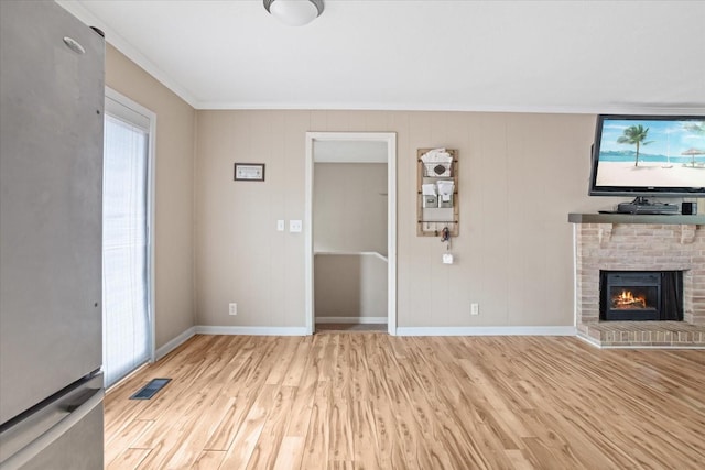 unfurnished living room with a fireplace, ornamental molding, and light wood-type flooring