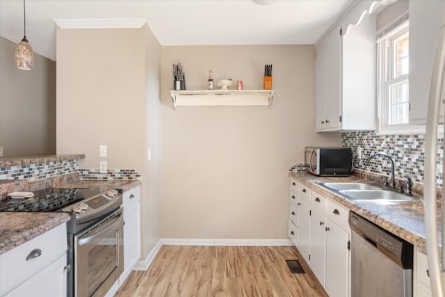 kitchen with sink, white cabinetry, hanging light fixtures, appliances with stainless steel finishes, and light hardwood / wood-style floors