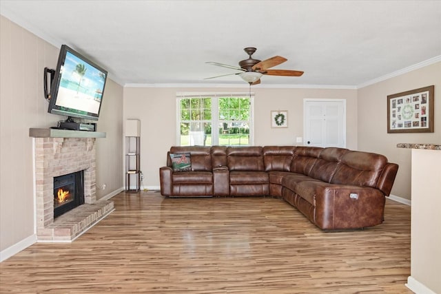 living room with hardwood / wood-style floors, crown molding, a brick fireplace, and ceiling fan