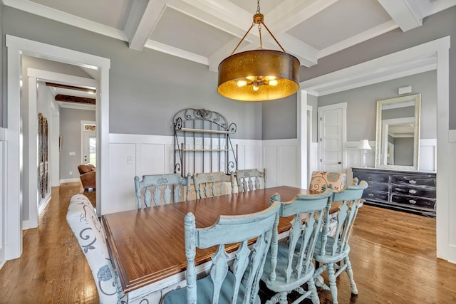 dining space with coffered ceiling, wood-type flooring, ornamental molding, and beamed ceiling