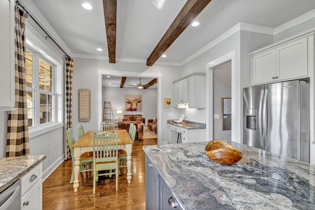 kitchen featuring decorative backsplash, beamed ceiling, white cabinets, and appliances with stainless steel finishes