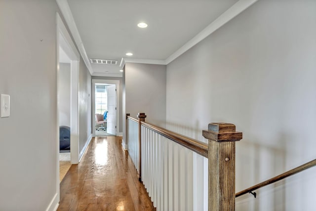 hallway with ornamental molding and light hardwood / wood-style floors