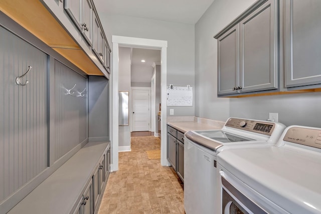 clothes washing area with washer and clothes dryer and cabinets