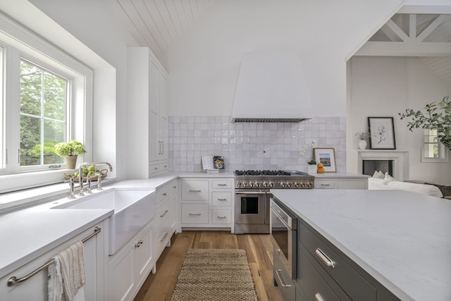 kitchen with white cabinetry, light hardwood / wood-style flooring, tasteful backsplash, and stainless steel appliances