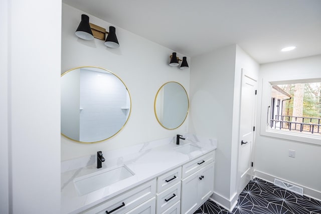 bathroom with double vanity, a sink, visible vents, and baseboards