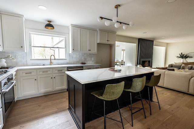 kitchen with tasteful backsplash, a kitchen island, open floor plan, oven, and white cabinetry