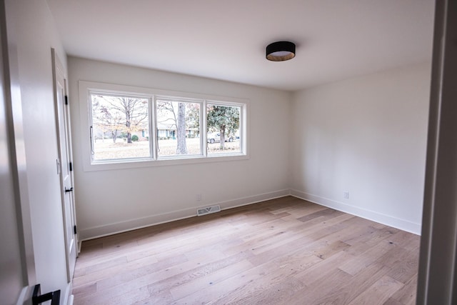 spare room featuring light wood-type flooring, baseboards, and visible vents