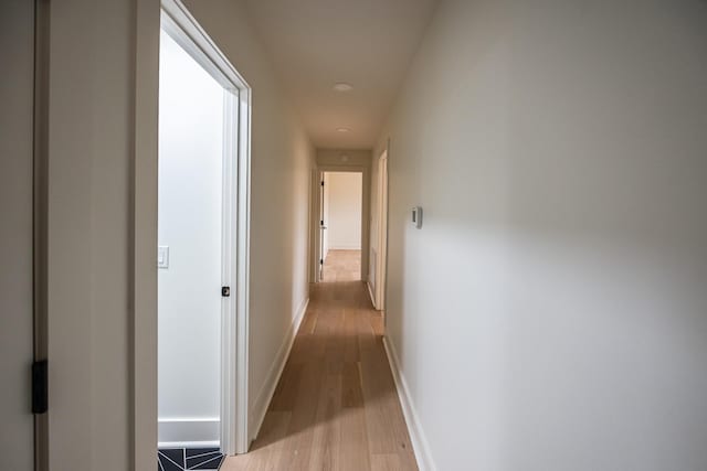 corridor featuring light wood-style floors and baseboards