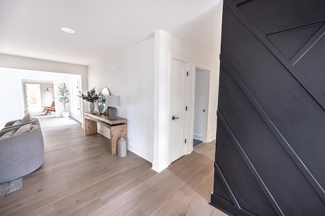 hall with light wood-style floors, baseboards, and recessed lighting