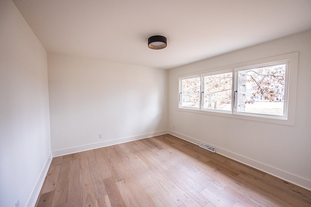 unfurnished room featuring light wood-style flooring, visible vents, and baseboards