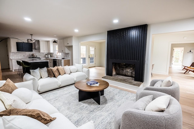 living room with baseboards, light wood-type flooring, a fireplace, and recessed lighting