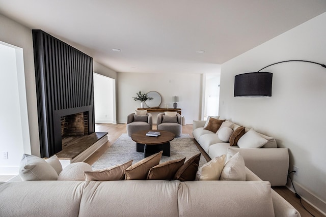 living area with light wood-style floors, baseboards, and a fireplace with raised hearth