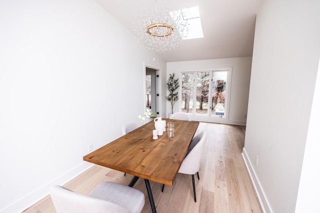 dining area with vaulted ceiling with skylight, light wood-style flooring, and baseboards