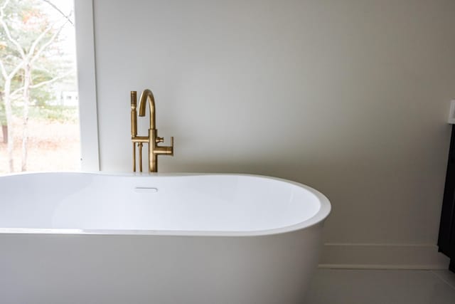 full bath featuring a soaking tub and tile patterned flooring