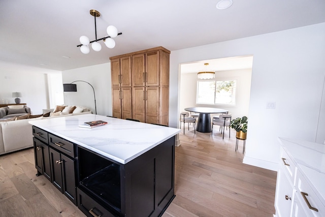 kitchen featuring light stone counters, a center island, brown cabinets, hanging light fixtures, and open floor plan