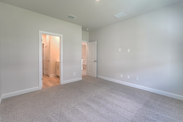 unfurnished bedroom featuring connected bathroom and light colored carpet