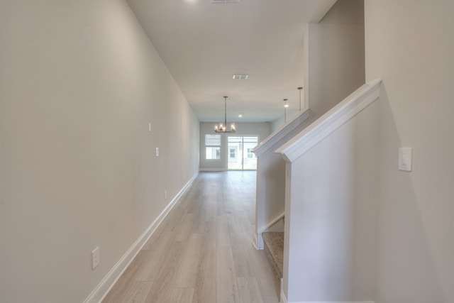 corridor featuring a chandelier and light hardwood / wood-style floors