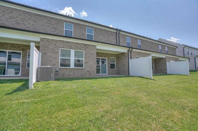 rear view of property with central AC and a lawn