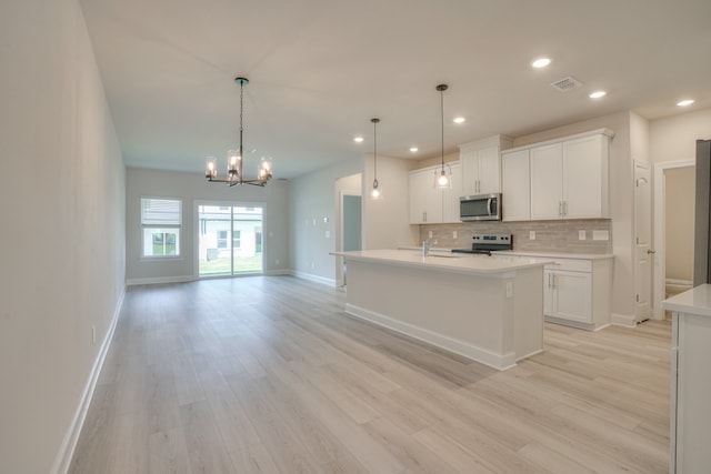 kitchen featuring white cabinetry, hanging light fixtures, a kitchen island with sink, stainless steel appliances, and light wood-type flooring