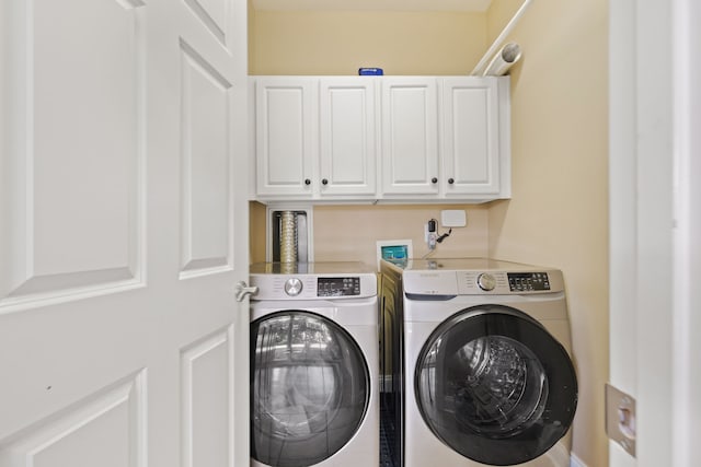 laundry area featuring washing machine and clothes dryer and cabinets