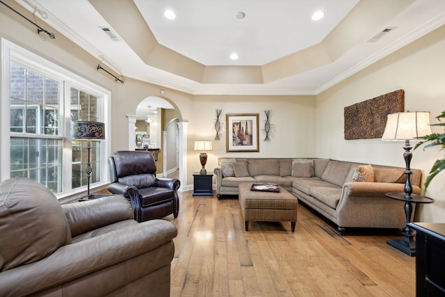 living room with crown molding, a tray ceiling, and light hardwood / wood-style flooring