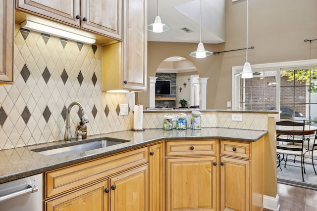 kitchen featuring dark stone countertops, dark wood-type flooring, sink, decorative light fixtures, and backsplash