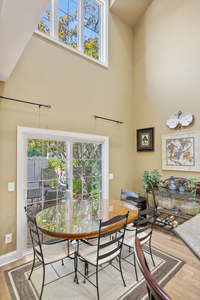 dining space with high vaulted ceiling, a healthy amount of sunlight, and hardwood / wood-style floors