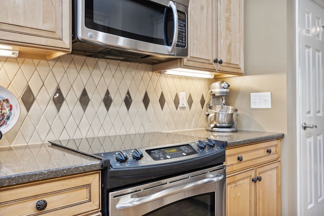 kitchen featuring tasteful backsplash, dark stone counters, appliances with stainless steel finishes, and light brown cabinetry