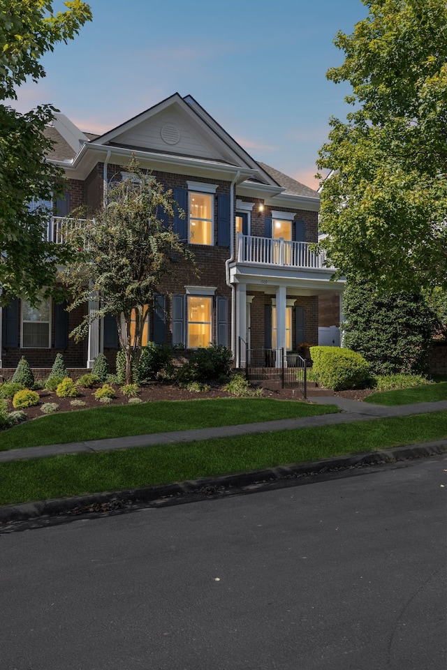 view of front of house featuring a balcony and a lawn