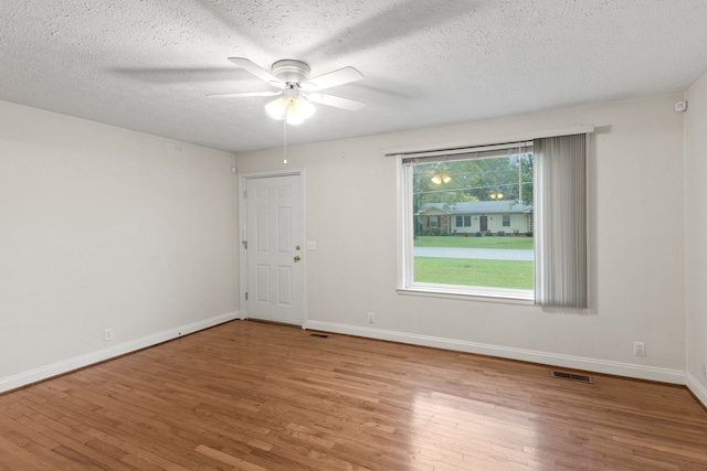 empty room with ceiling fan, a textured ceiling, and light hardwood / wood-style flooring