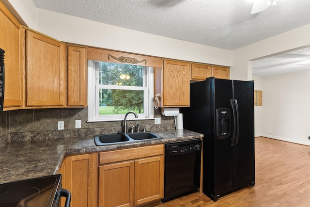 kitchen with sink, tasteful backsplash, black appliances, light hardwood / wood-style floors, and a textured ceiling