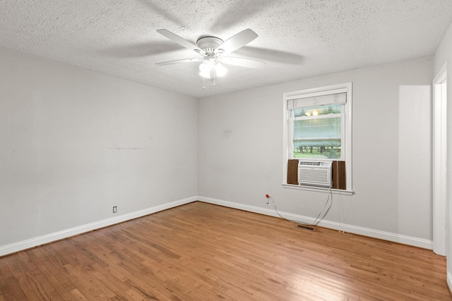 empty room featuring cooling unit, ceiling fan, light hardwood / wood-style floors, and a textured ceiling