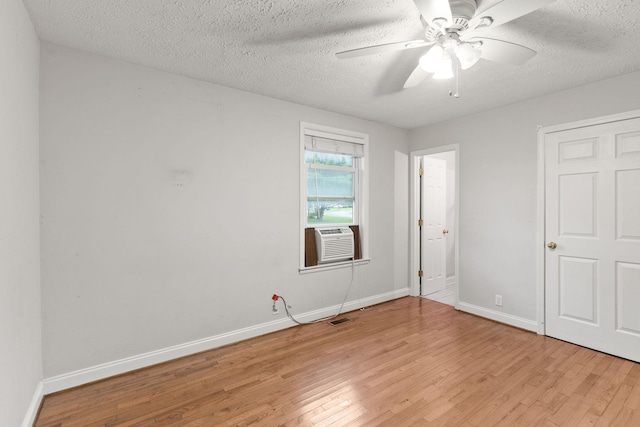 spare room with ceiling fan, cooling unit, a textured ceiling, and light wood-type flooring